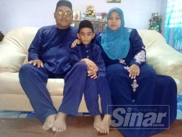 Muhammad Irfan (tengah) bersama ibu dan bapa angkatnya. 