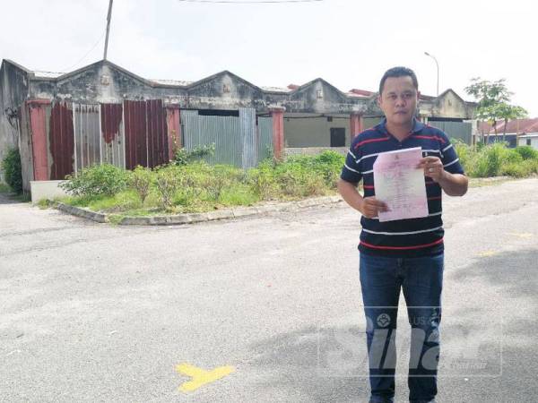 Hasbi Yullah menunjukkan dokumen mengenai pembelian kedai yang diceroboh individu tidak bertanggungjawab di Taman Muara Esbee.