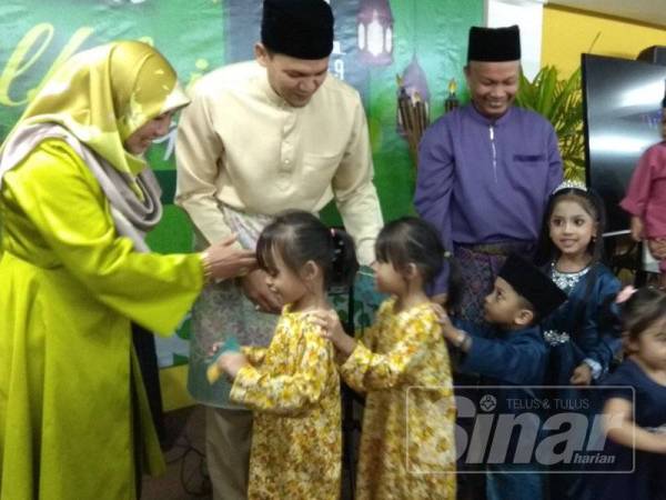 Noraini (kiri) turut memberi sumbangan duit raya kepada kanak-kanak yang hadir pada majlis hari ini.