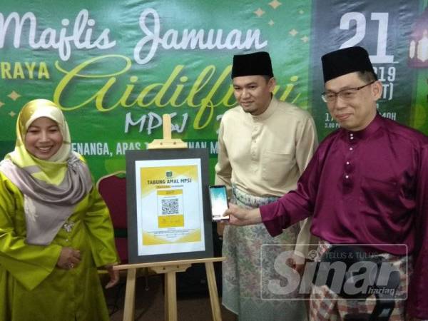 Salah seorang penyumbang Tabung Amal MPSJ menunjukkan cara menderma dengan menggunakan kaedah QR pay-Maybank sambil diperhatikan Noraini (kiri).