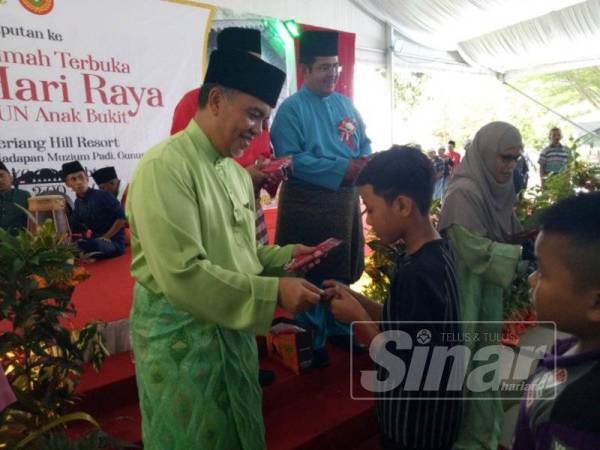 Amiruddin menyampaikan duit raya kepada kanak-kanak yang hadir di majlis rumah terbukanya di sini hari ini.