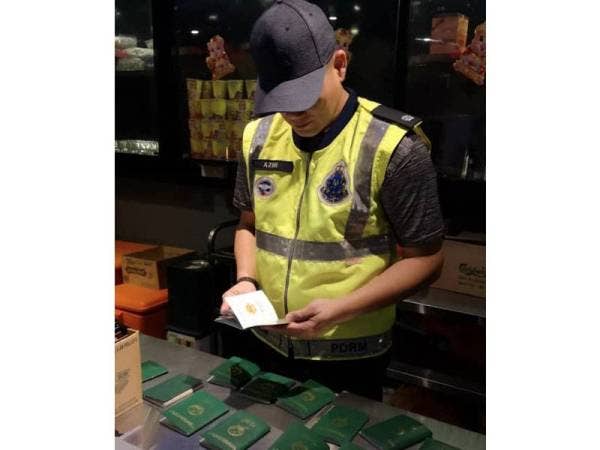 Azmi memeriksa pasport serta beberapa barangan lain yang dirampas dalam serbuan. - Foto Polis Selangor