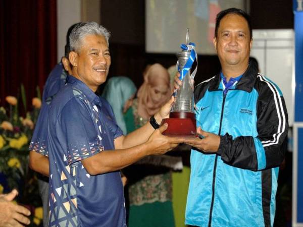 Pengarah Pengurusan Bukit Aman Datuk Abd Rahim Jaafar (kiri) menyerahkan piala juara acara dart kepada wakil dari Kontinjen Johor pada Majlis Penutup Kejohanan Sepak Takraw, Karom, Dart dan Catur di Dewan Tan Sri Khalid Abu Bakar, Pulapol, Kuala Lumpur hari ini. - Foto Bernama