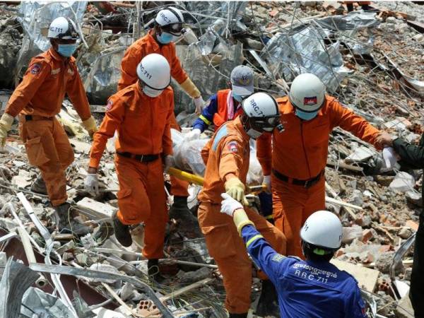 Pasukan penyelamat membawa keluar mayat mangsa daripada sisa runtuhan bangunan.