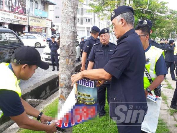 Zainuddin (kanan) turut membantu menurunkan gegantung pinjaman along di Simpang Kuala, Alor Setar semalam.