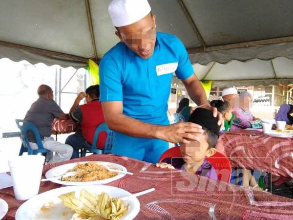 Ahmad membetulkan songkok adik bongsunya yang turut hadir bagi meraikan hari raya bersama.