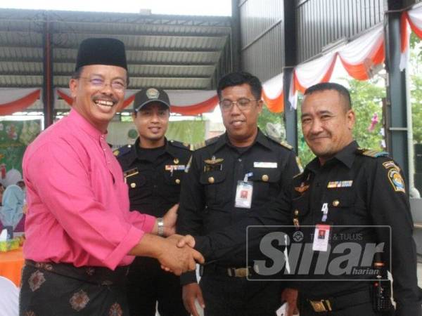 Mohd Azam (kiri) bersalaman dengan anggota penguatkuasaan dari Thailand yang hadir ke Majlis Sambutan Hari Raya Aidilfitri Maqis Wilayah Timur di Rantau Panjang.