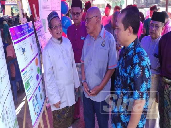 Abdul Yunus (dua, kanan) berkesempatan menyampaikan sumbangan duit raya kepada kanak-kanak yang hadir ke Majlis Rumah Terbuka Aidilfitri TNB di Kampung Dew, hari ini.