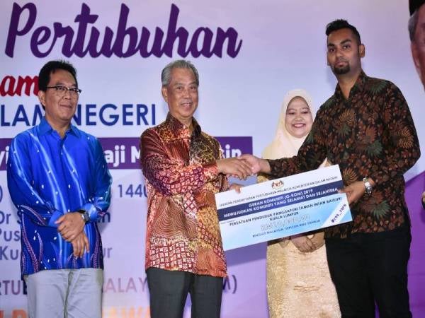 Muhyiddin (dua, kiri) menyampaikan replika cek Geran Komuniti (G-KOM) 2019 kepada wakil Persatuan Penduduk Pangsapuri Taman Intan Baiduri Kuala Lumpur pada Program Kelestarian Pertubuhan Pendaftar anjuran Jabatan Pendaftar Pertubuhan Malaysia (JPPM) hari ini. - FOTO BERNAMA
