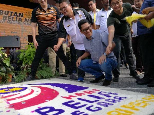 Ahmad Faizal melihat lakaran yang dibuat dengan beras pada majlis berkenaan, hari ini.