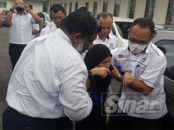 Pengarah Kesihatan negeri, Dr Selahuddeen Abdul Aziz (kiri) membantu antara murid yang mengalami gangguan kesihatan ke kereta sebelum dibawa ke klinik kesihatan berhampiran untuk mendapatkan rawatan.