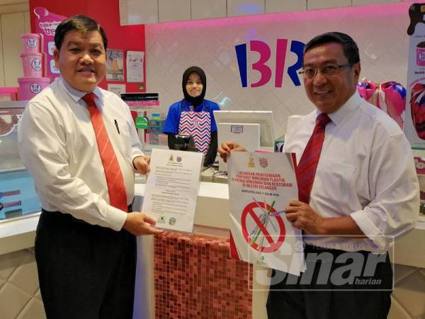 Loy Sian (kiri) dan Haris mengedarkan notis pemberitahuan Kempen Bebas Straw Plastik di premis makanan di Plaza Shah Alam hari ini.