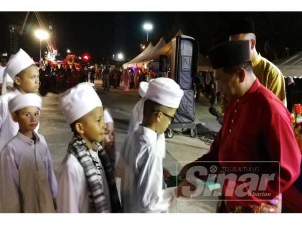 Mohamad Shoki menyampaikan duit raya kepada tetamu yang hadir.