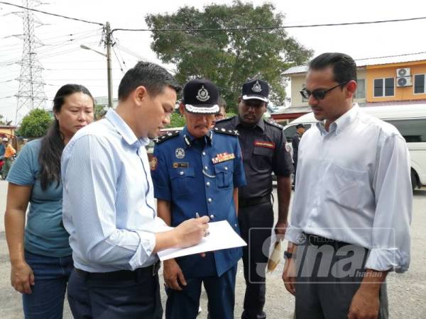 Zulkurnain (kiri) menyemak jumlah premis yang diarah tutup dalam operasi bersepadu di Serdang Jaya 5 dan 6 hari ini.