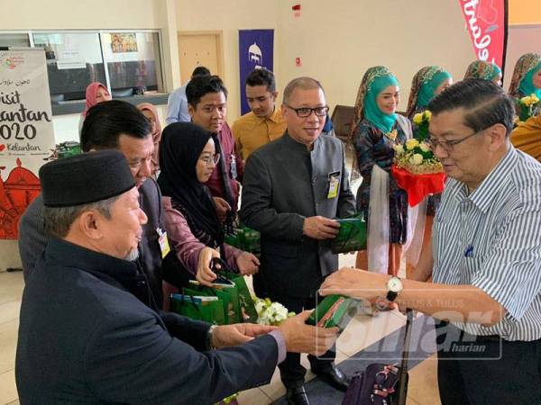 Hassan (kiri) menyambut ketibaan pelancong dari Singapura yang menggunakan penerbangan Scoot hari ini.