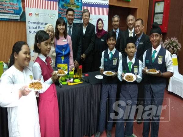 Nie Ching (empat, kanan) bersama Pengerusi Gardenia Bakeries (KL) Sdn Bhd, Datuk Mohammad Zainal Shaari (lima, kanan) serta murid-murid SK Bukit Jelutong mencuba produk NuMee yang dimasak ketika program Pemakanan Sihat Bersama Numee 2019 hari ini.