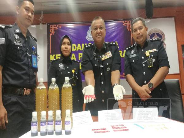 Amran (dua dari kanan) menunjukkan dadah yang dirampas pada Ops Sarang Khas.