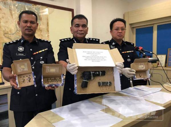 Abdul Rahim (tengah) bersama pegawai menunjukkan pistol dan peluru yang dirampas daripada suspek di sebuah rumah dua tingkat di Jalan Telipot.