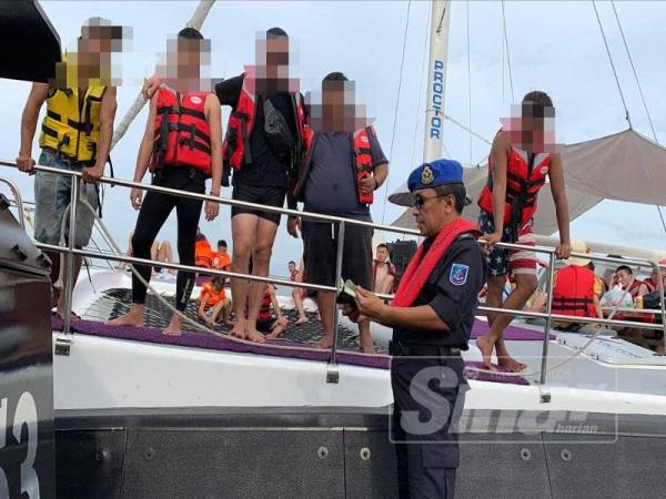 Rohizan sedang melakukan pemeriksaan terhadap bot persiaran pelancong yang melanggar syarat lesen membawa lebihan penumpang di perairan Selat Penarak, petang semalam.