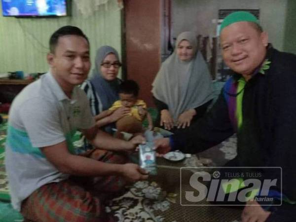 Abdullah (kiri) menerima sumbangan daripada Ku Mohd Zaki di kediaman keluarganya di Jelawang, Dabong, hari ini.