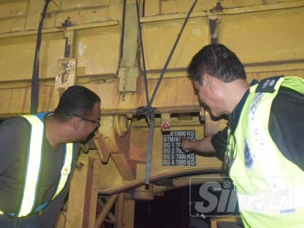 Muhammad Firdaus (kiri) melihat sebuah treler yang dikesan membawa lebihan muatan pasir pada operasi malam tadi.