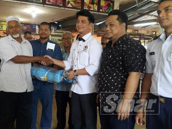 Muhammad Faiz (tiga dari kanan) memyampaikan sumbangan pukat kepada nelayan tradisional petang tadi.