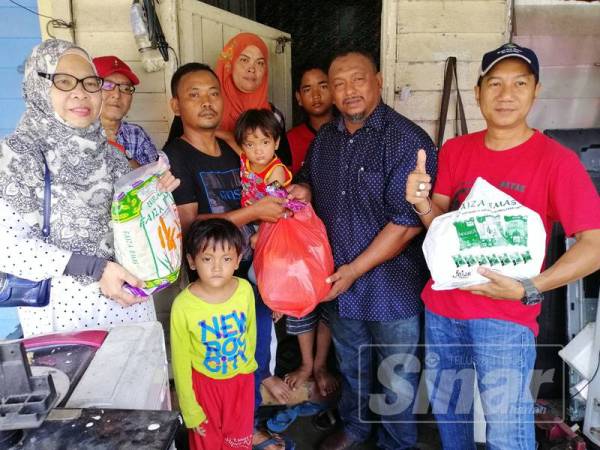 Mohd Hamidi (dua, kanan) menyerahkan sumbangan kepada Mohd Norashid (tiga, kiri) di Kampung Parit Imam, Batu Pahat.