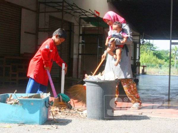 Peniaga membersihkan kawasan premis perniagaan mereka yang terkesan akibat kejadian ribut.