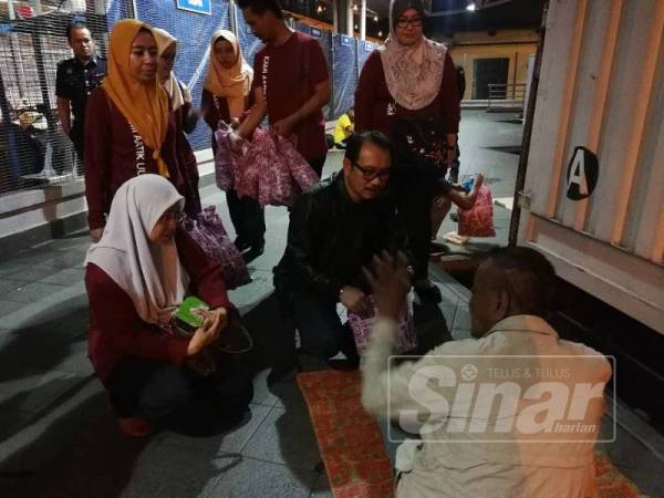 Zamrud ( tengah) bertanyakan sesuatu kepada gelandangan ketika program menyantuni mereka diadakan di CIQ Johor Bahru.