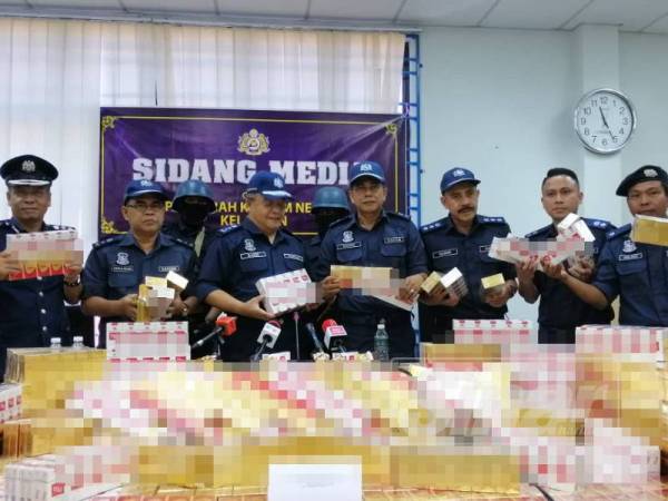 Mohd Rakbi (tiga, kiri) bersama pegawai dan anggota JKDM menunjukkan rokok seludup yang dirampas.