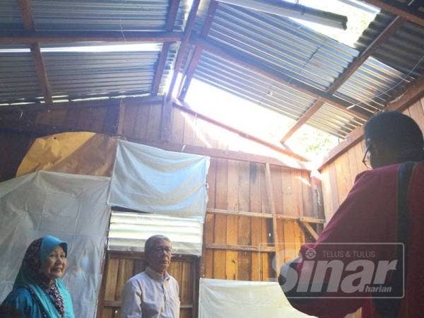 Kamaruddin meninjau rumah Zainun yang rosak akibat ribut petang semalam.