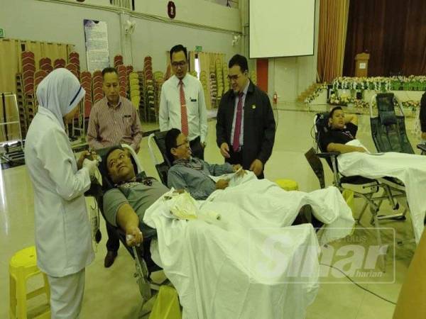 Mohd Fikri (kanan) bersama pelajar yang sedang menderma darah pada Program Derma Darah Perdana PSMZA.