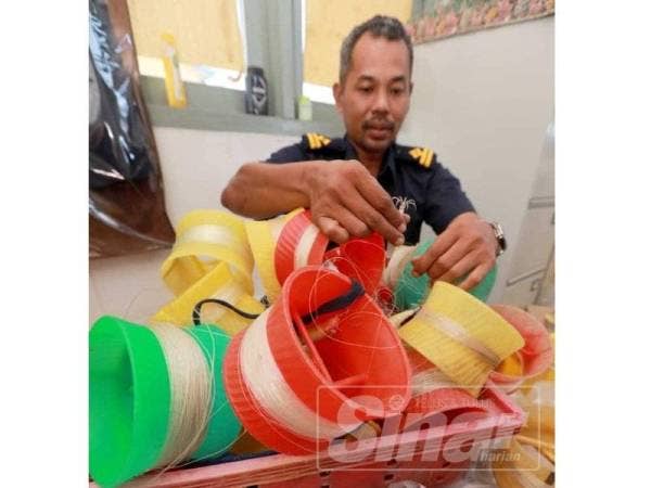 Pegawai Penyiasat Bahagian Perlindungan Sumber Jabatan Perikanan Pahang Mohd Affendy Abdul Manap menunjukan alat mencandat sotong yang dirampas.