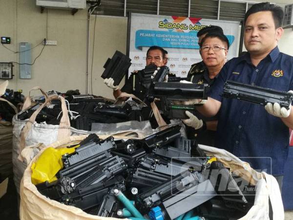 Mohd Ridzuan (kanan) menunjukkan katrij dan toner yang dirampas KPDNHEP sebelum ini.