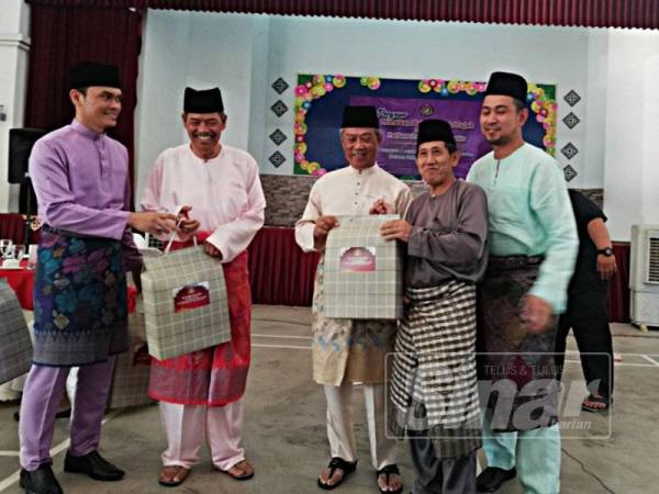Muhyiddin (tengah) menyampaikan sumbangan kepada bakal haji, Atiman Kadar, di Dewan Sekolah Kebangsaan Sri Bukit Pasir, Muar.