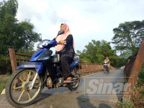 Penduduk Kampung Empa melalui jambatan besi yang uzur di kampung mereka.