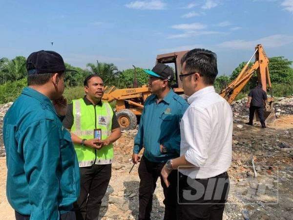 Wei Kiat (kanan) turut serta dalam operasi tindakan ke atas tapak pembuangan sampah haram di Taman Saujana semalam.