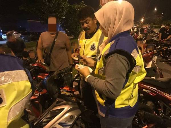Polis memeriksa salah seorang penunggang motosikal dalam Ops Samseng Jalanan. - FOTO POLIS