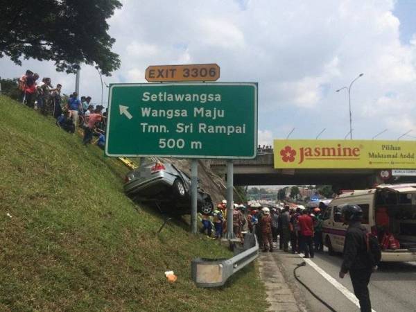 Keadaan kereta yang terbabas tersangkut pada tiang papan tanda jalan selepas melanggar pengadang jalan. Foto: JBPM KL