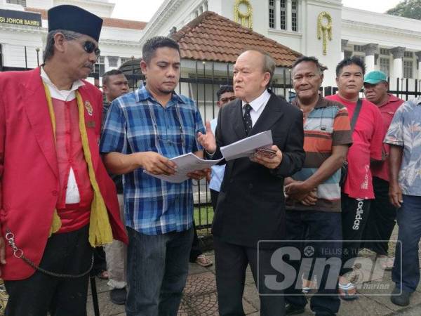 Kamaruddin berkata sesuatu kepada bapa kepada mangsa, Idham Wazir A.Wahab yang turut hadir di pekarangan Mahkamah Tinggi Johor Bahru, hari ini.
