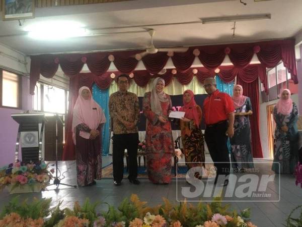 Rina menyampaikan sumbangan kepada salah seorang wakil sekolah Parlimen Titiwangsa.