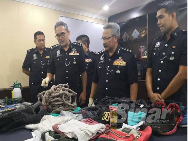 Mohamad (tiga dari kanan) menunjukkan antara barangan yang dirampas.