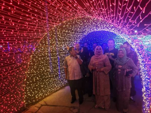 Shahaniza (tengah) tertarik melihat kerlipan lampu LED yang disediakan di karnival tersebut.