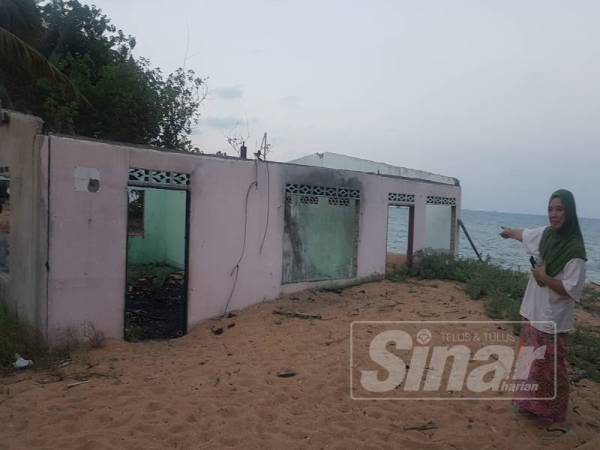 Normah menunjukkan keadaan rumah jiran belakang rumahnya yang ranap dipukul ombak dan memaksa jirannya itu berpindah Disember lalu.