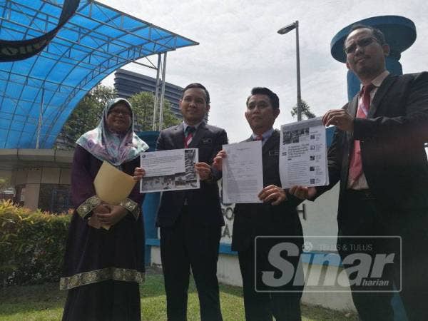 Jasri (dua, kanan) menunjukkan laporan polis yang dibuatnya di IPD Putrajaya, hari ini.