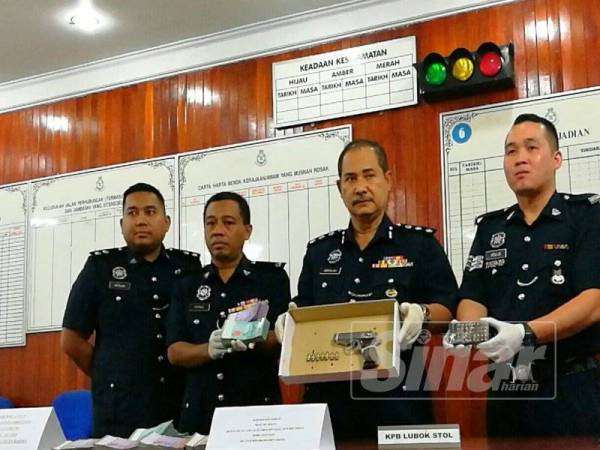 Abdullah (dua dari kanan) menunjukkan pistol dan wang tunai yang dirampas di rumah sewa keluarga warga Thailand tersebut.