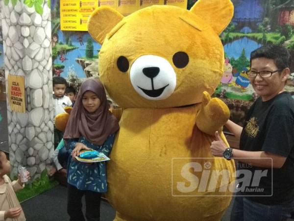 Salah seorang peserta pertandingan mewarna (kiri) yang mendapat tempat pertama bergambar bersama maskot Teddy.