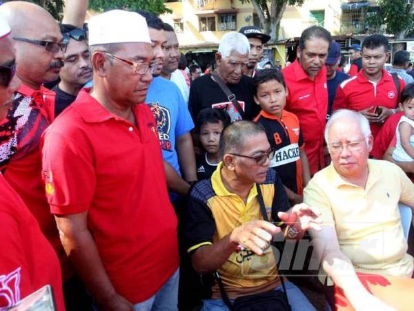 Najib (duduk, tengah) sedang mendengar keluhan nelayan ketika bertemu nelayan dan meninjau tapak cadangan projek tambak laut itu di Permatang Damar Laut, Teluk Kumbar.