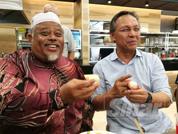 Hasni (kanan) dan Abdullah menikmati durian serta manggis sempena program Kenduri Durian anjuran Zainal's Place hari ini.