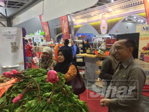Abdul Yunus (kanan) melihat rakyat Singapura membeli petai yang dibawa dari Perak pada Malaysia Fest 2019 di Bangunan Expo, Changi, Singapura.